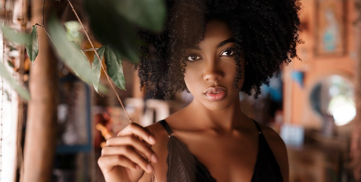 Black woman holding a tree branch with a blurred indoor background